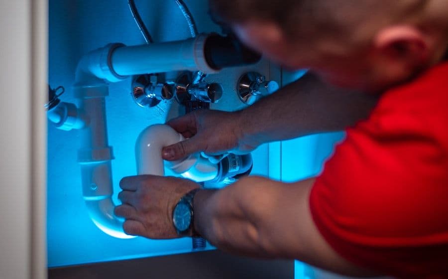 Plumber repairing the supply lines and P-trap under a sink